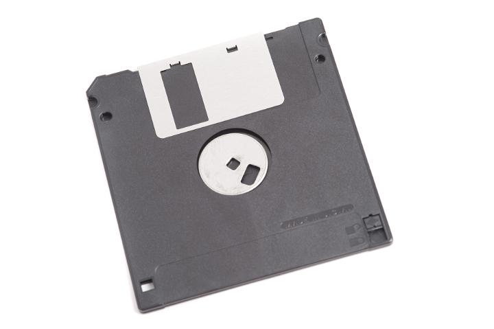 Black floppy disk or diskette, old-fashioned medium used for data storage, close-up isolated on white