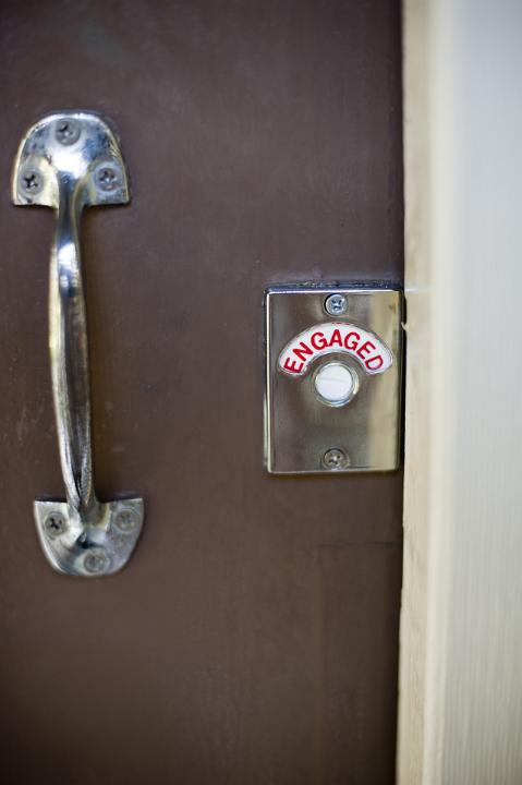Close Up Detail of Door Handle and Lock Sign Indicated that Room is Engaged or Occupied