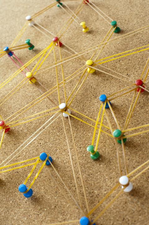 Networking concept formed from rubber bands connecting bright colorful pins on a cork board