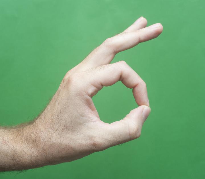 Close up Man Hand Showing Okay or Alright Sign Isolated on Green Background.