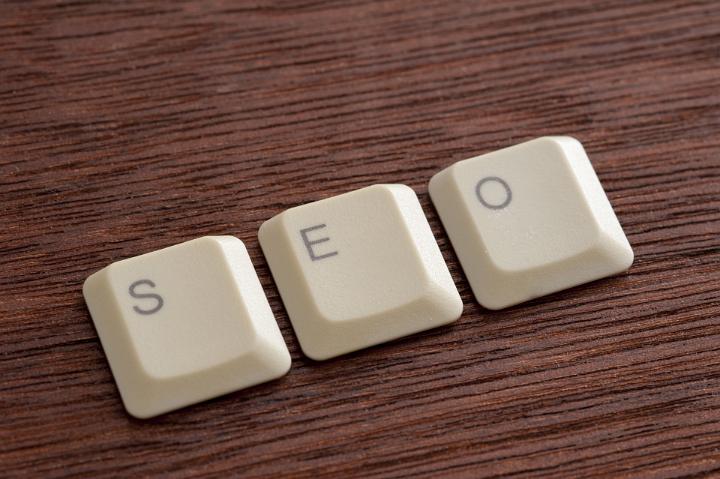 Computer keyboard keys arranged in seo word against wooden surface