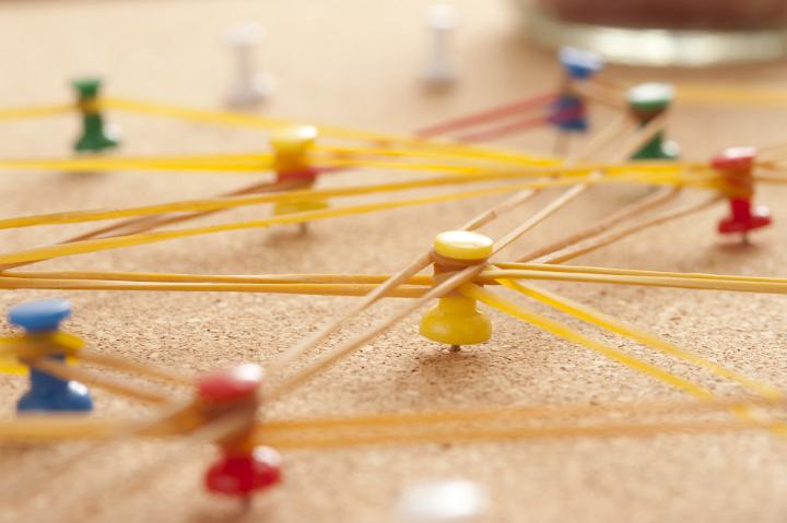 Team Concept - Close up Colored Pins on Cork Board Connected with Rubber bands