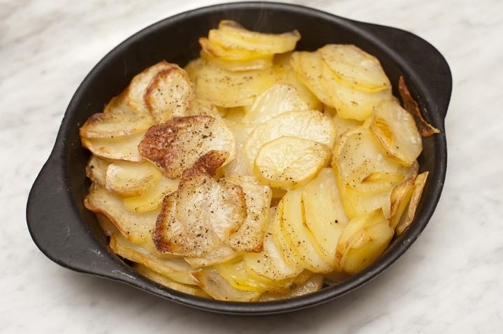View from above of a dish of fresh sliced oven baked potatoes au gratin sprinkled with melted cheese