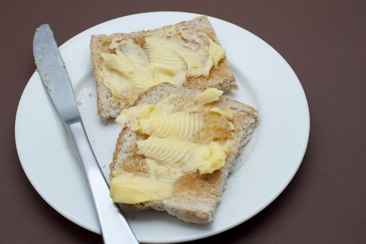 Two slices of buttered toast on a plate ready for morning breakfast, high angle view with a knife