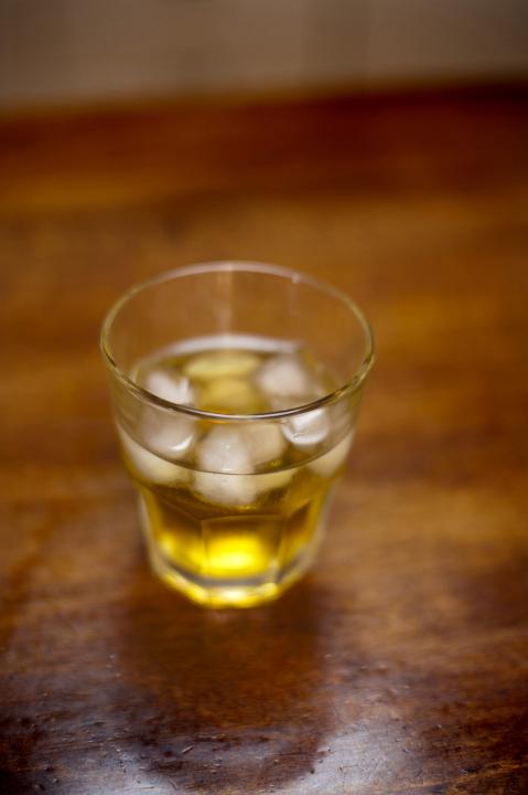 Close up Single Glass of Spirit with Ice on Top of Wooden Table.