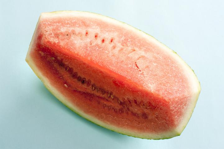 Large slice of fresh juicy watermelon for a refreshing summer treat viewed from above on light blue