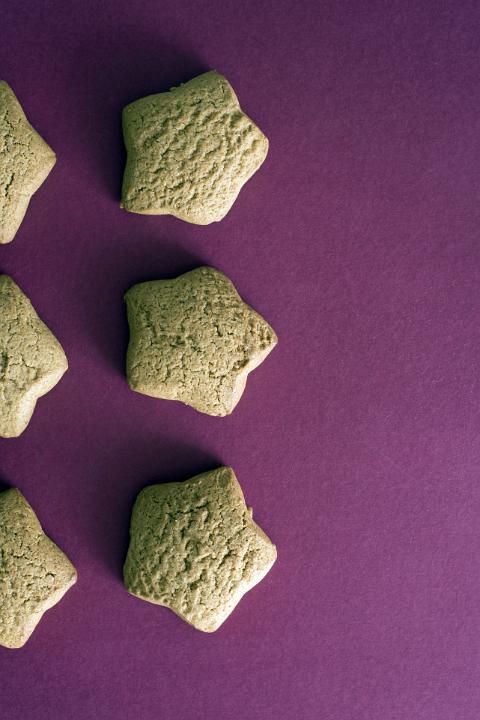 A close up, abstract crop of six star shaped festive cookies isolated on a plain purple background with copy space.