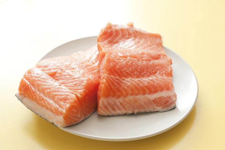 Fresh uncooked filleted fish steaks on a plate, probably salmon or freshwater trout due to the succulent pink flesh, ready for cooking for dinner