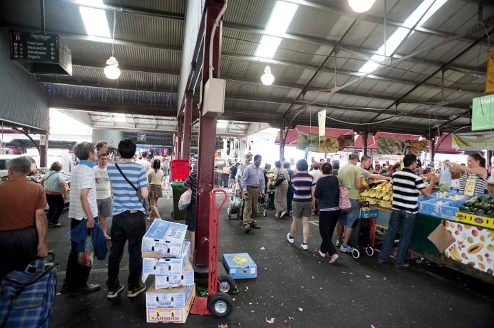 Shoppers purchasing fresh produce in a busy undercover fruit market