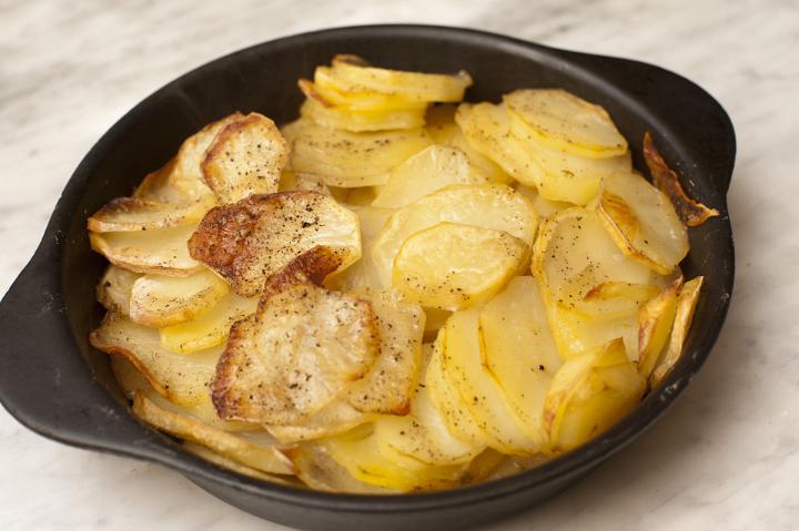 Close up Tasty Gratinated Potato Slices on Black Bowl, Placed on Wooden Table