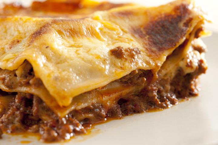 Serving of juicy meaty Italian spaghetti with pasta sheets topped with cheese and ground beef in a delicious homemade recipe