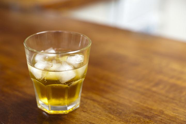 Liquor Concept - Close up Glass of Cold Whiskey Drink with Ice Cubes on Top of Wooden Table.