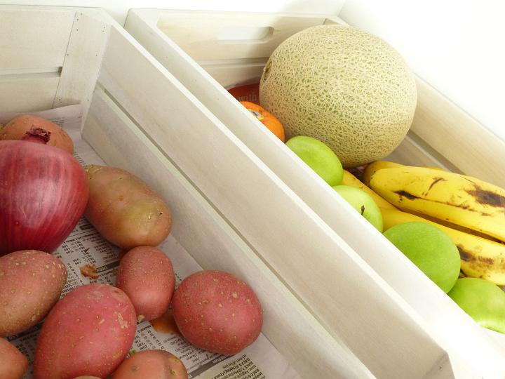 Selection of fresh fruit and vegetables at market in wooden crates with potatoes, onion, apples, melon and bananas
