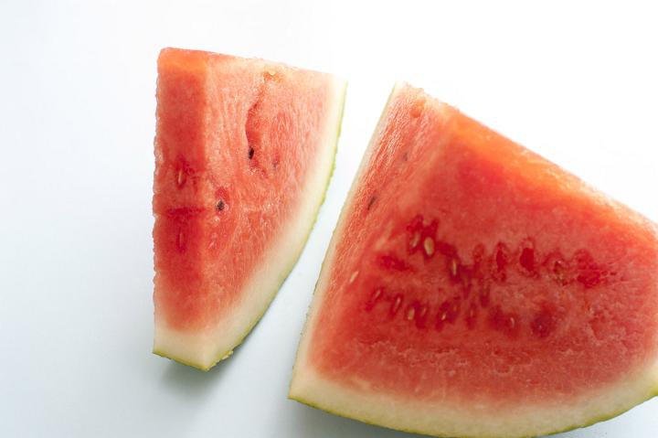 Two pieces of watermelon in close-up against plain background