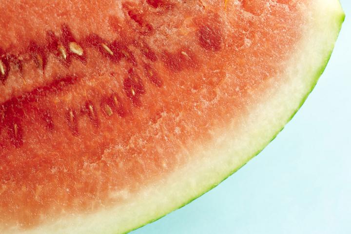 A close up dissection of a freshly cut, juicy red watermelon isolated on a plain white background.