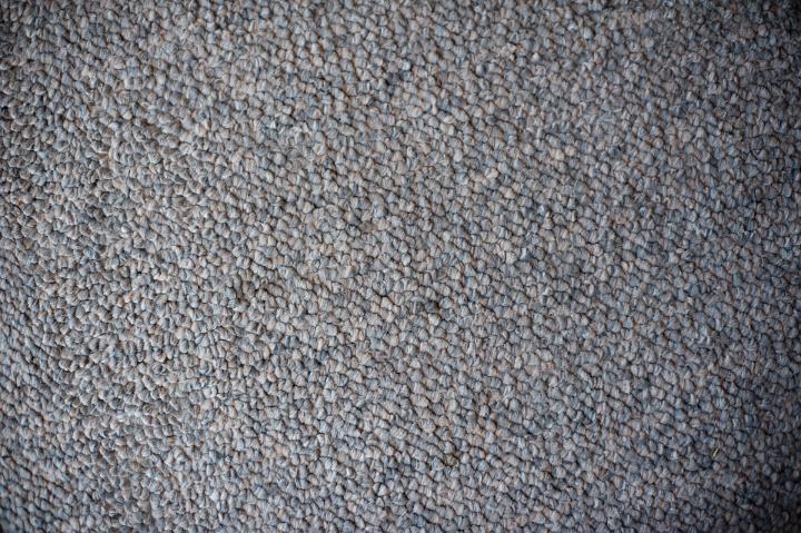 Grey carpet background texture showing the warp, weft and pattern of the weave in the pile, full frame with corner vignettes