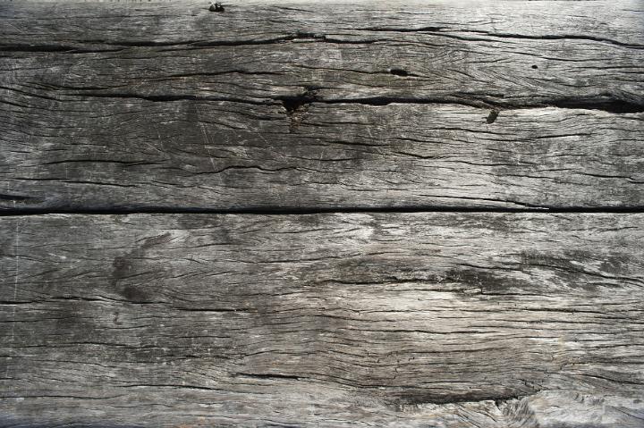 Dried weathered wooden boards background texture with a cracked desiccated greyish grunge surface, full frame