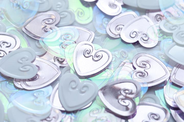 Scattered collection of silver wedding hearts in a close up full frame view symbolic of love and romance