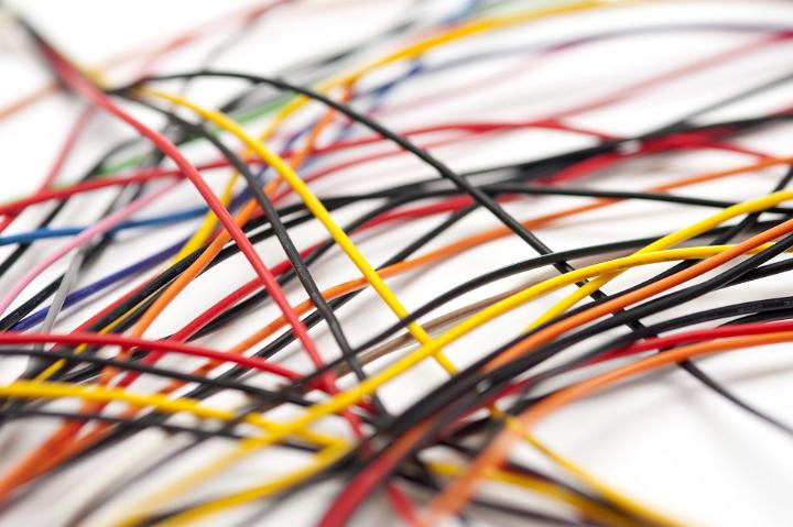 Tangle of colorful plastic coated electric wires and cables lying on a white background, low angle view