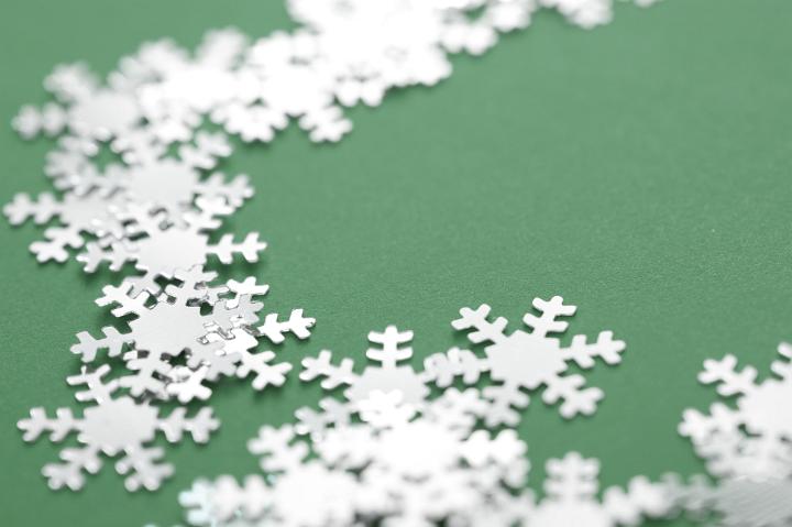 Christmas background of winter snowflakes winding across a green background with shallow dof to the centre and copyspace for your seasonal greeting