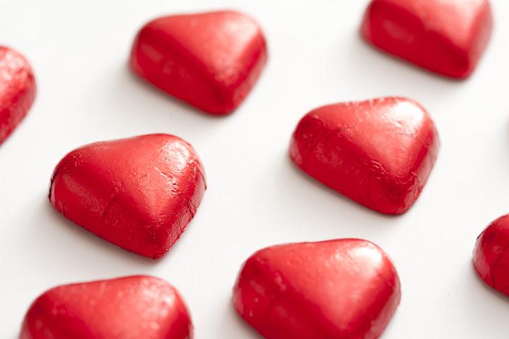 Foil wrapped red chocolate valentine hearts isolated on white background with copy space.