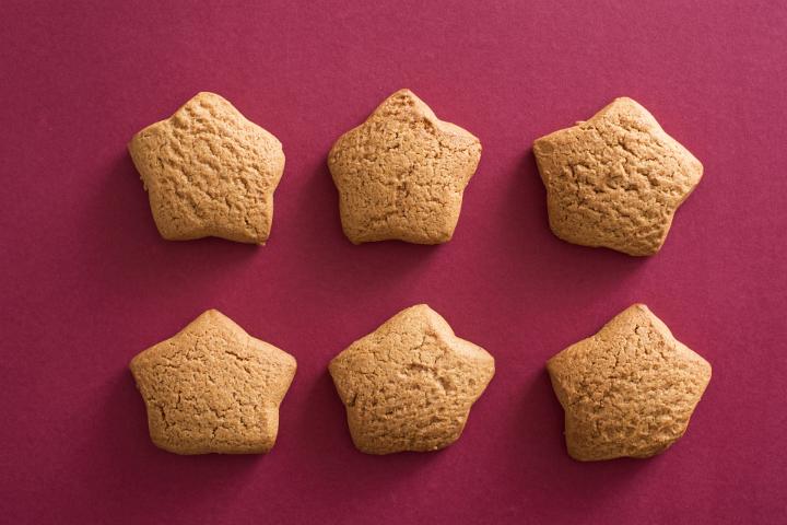 Six star shaped cookies in two rows on a festive red background for celebrating Christmas and New Year