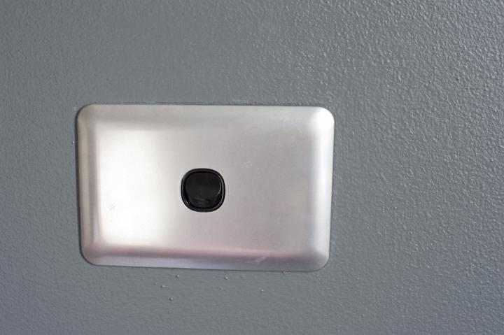 Empty wall mounted white plastic antenna socket in a grey wall for inserting a TV cable connection to the exterior antenna