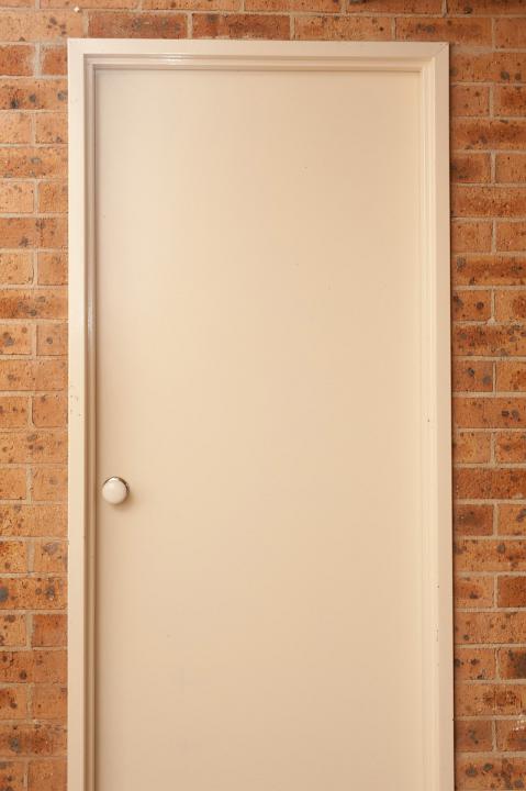 Close Up Architectural Detail of Closed Interior White Door with Door Knob in Brick Wall