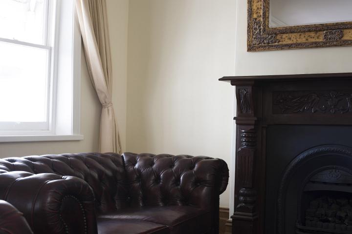 Comfortable leather armchair in a study or living room placed below a window with beige curtain