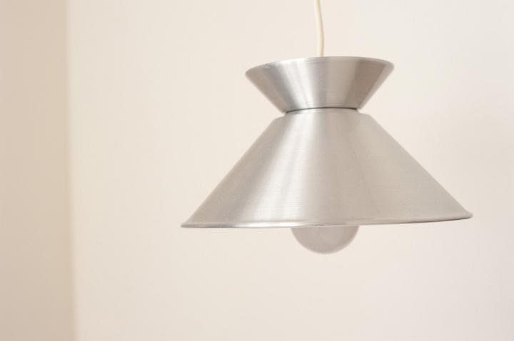 Stylish simple metal light fitting hanging from the ceiling with a shiny silver metallic finish shade and globe - switched off