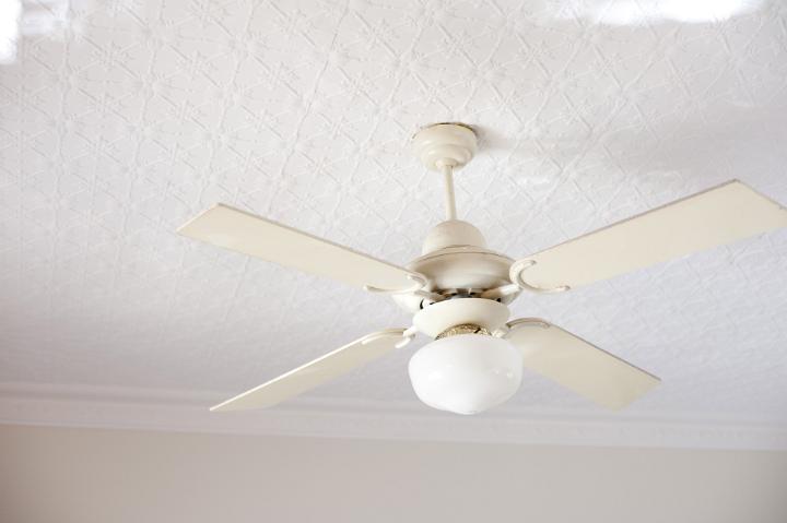 Retro ceiling fan with light fixture and four white blades for keeping cool in the summer heat