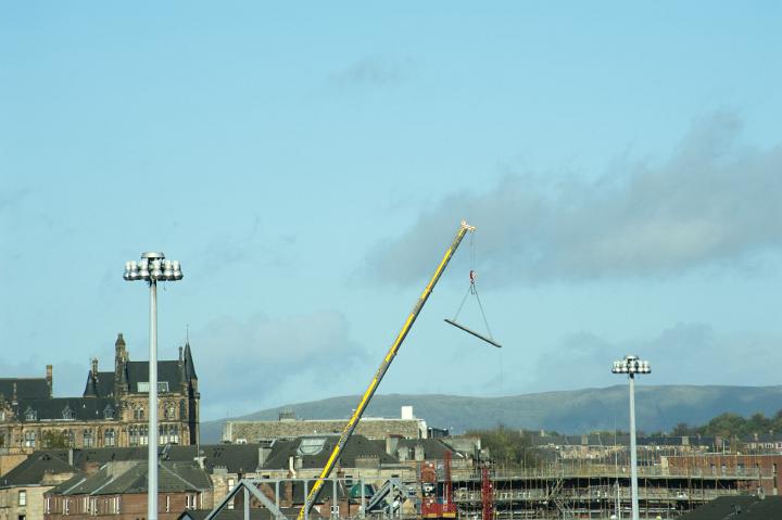 Construction Crane Lifting Beams Above Residential Rooftops in Urban Glasgow, Scotland