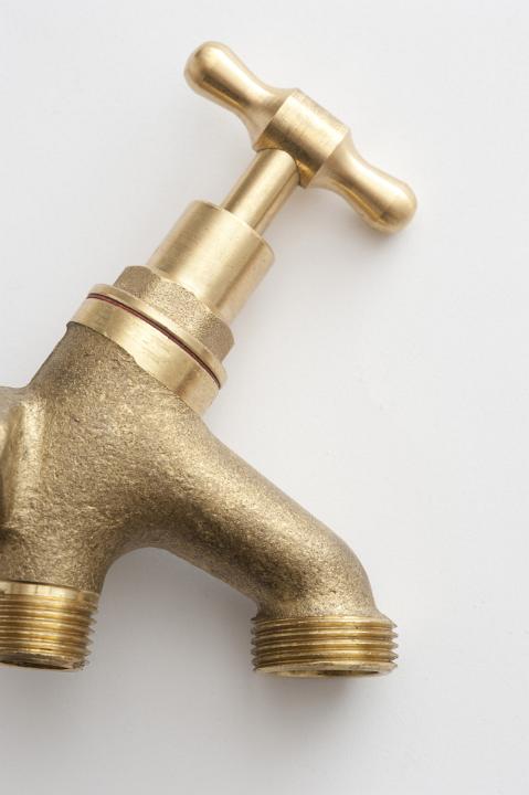 Close up of a brass metal garden tap isolated on a white background with copy space.
