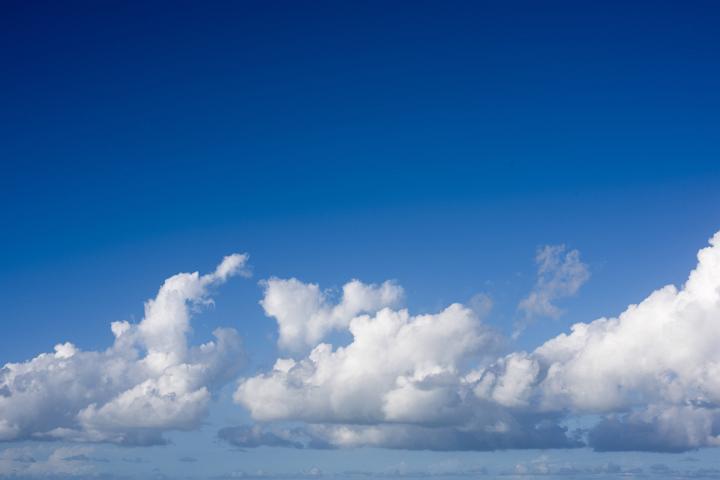 Pretty white fluffy formations of cumulus clouds in a sunny blue sky background conceptual of the weather, nature and the seasons