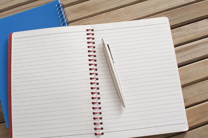 Close up Pen on Clean Open Spiral Notebook on Top of Wooden Table, Emphasizing Copy Space.
