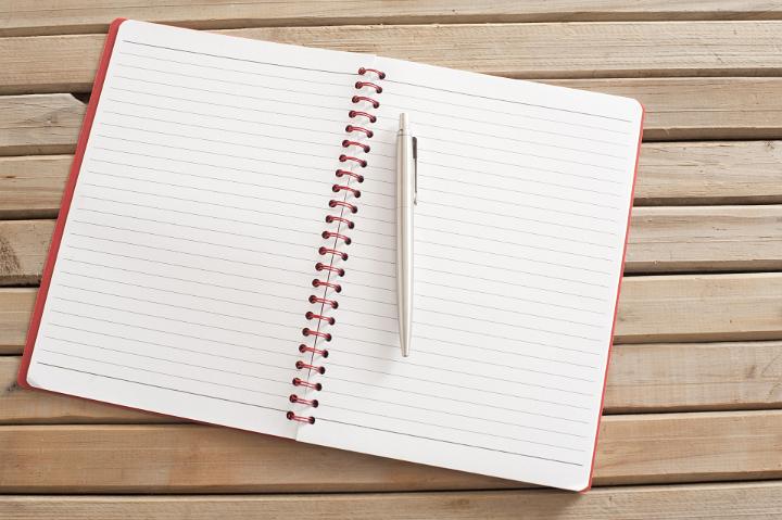 Close up Open Blank Spiral Notebook with Silver Ballpoint Pen on Wooden Table, Emphasizing Copy Space.