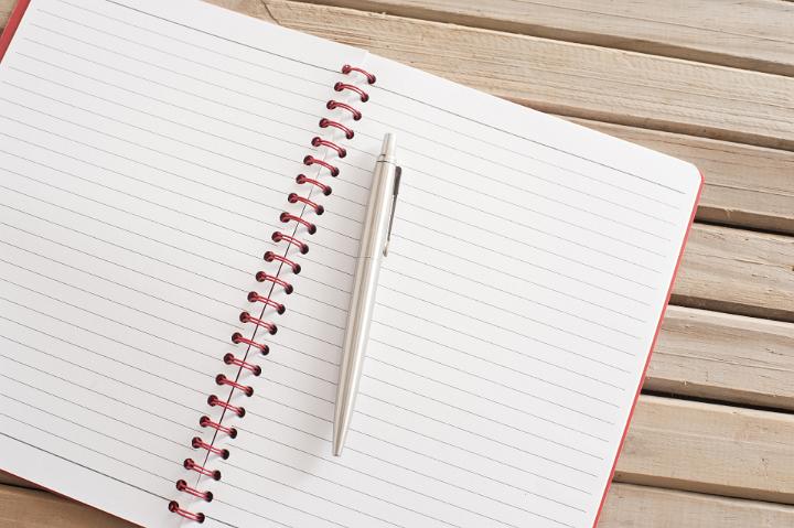 Close up Open Blank Spiral Notebook with Ballpoint Pen on Top Placed on Wooden Table.. Emphasizing Copy Space.