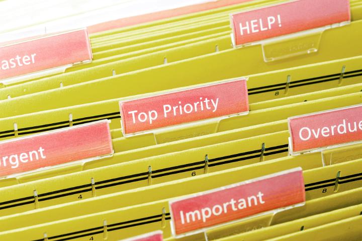Urgent Tasks Concept - Priority Files on Yellow Folders Inside a Shelf with Pink Labels