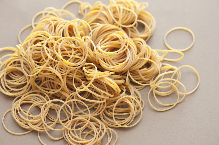 Close up Plenty of Tangled Rubber Bands on Top of Light Brown Table