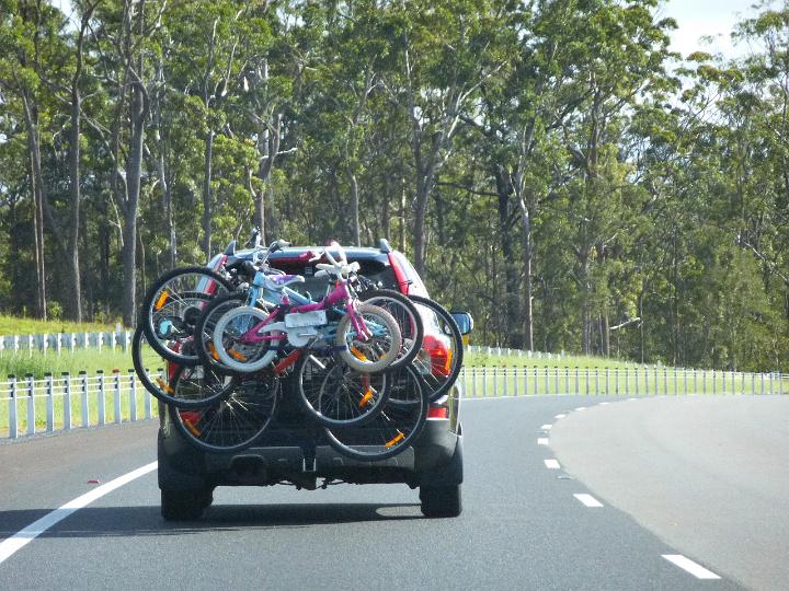 Car transporting bicycles for a cycle tour or weekend family outing with bicycles of all sizes strapped to the carrier as it travels along the motorway