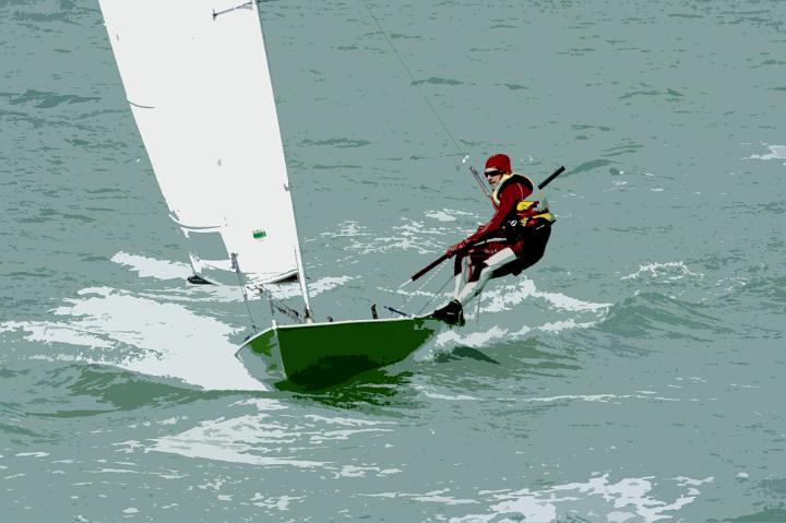 Man out sailing on a small sailboat using a trapeze to counterbalance his weight with the sail as he leans out over the ocean