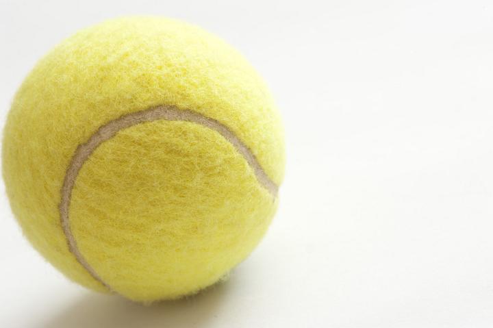 Close Up of Yellow Tennis Ball Showing Texture on White Background with Copyspace on Right Side