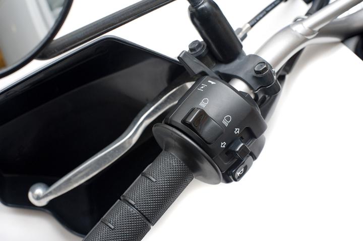 Close Up of Motorcycle Handlebar Grip and Guard with Brake Lever and Controls for Head Light, Turn Signal, and Horn