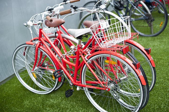 Two red bicycles parked on the green lawn outside a building conceptual of exercise, fitness and health