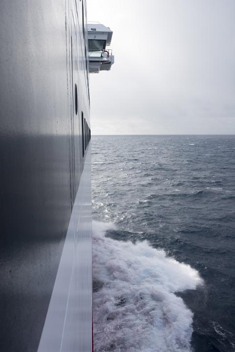 The view from a ferry window as it crosses a rough ocean towards a stormy horizon.