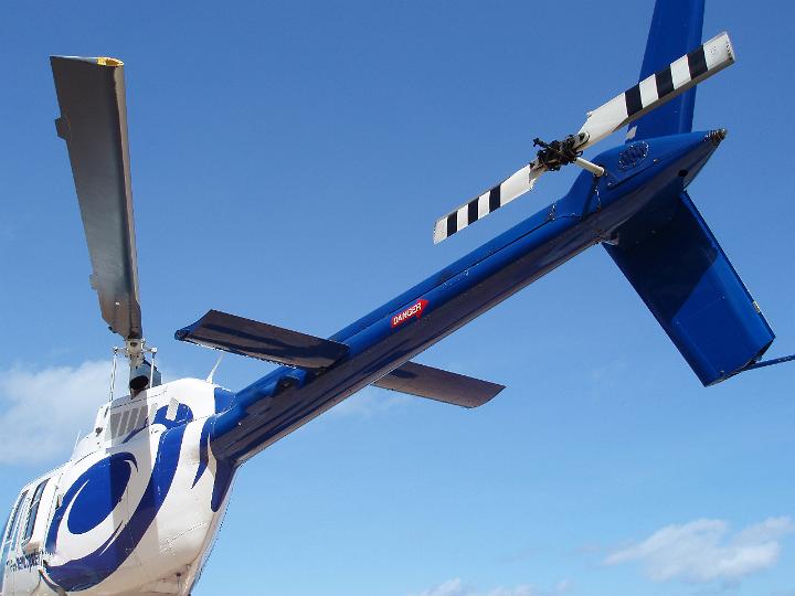 Blue helicopter tail rotor viewed from underneath looking up at a clear sunny blue sky