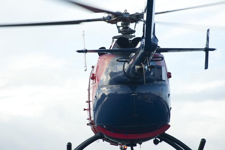 Helicopter taking off on a flight viewed from below the tail looking at the fuselage against a cloudy sky