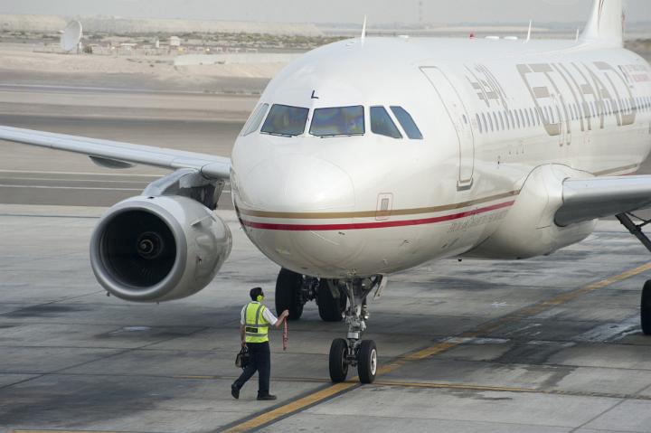 Marshal attendant parking an airplane on the apron aligning the front wheel with the yellow line