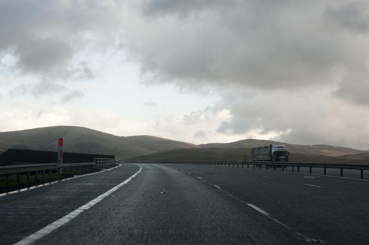 Traveling on a dual lane freeway with transport trucks and low lying stormy clouds, driver or passenger perspective