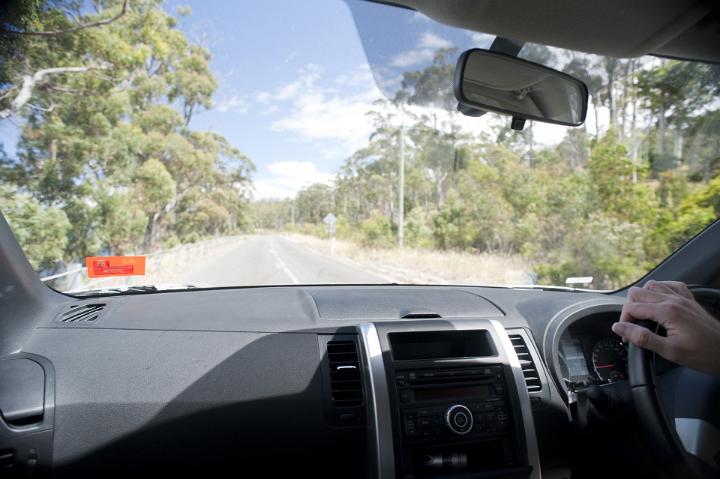 View through the windshield from the passenger perspective of driving along a tarred highway on a road trip, right hand drive vehicle